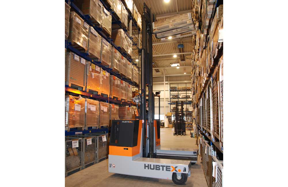 Hubtex 3-Wheel Electric Multidirectional Sideloader moving product from top shelf of pallet racking